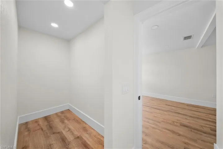 Hallway with light wood-style floors and recessed lighting