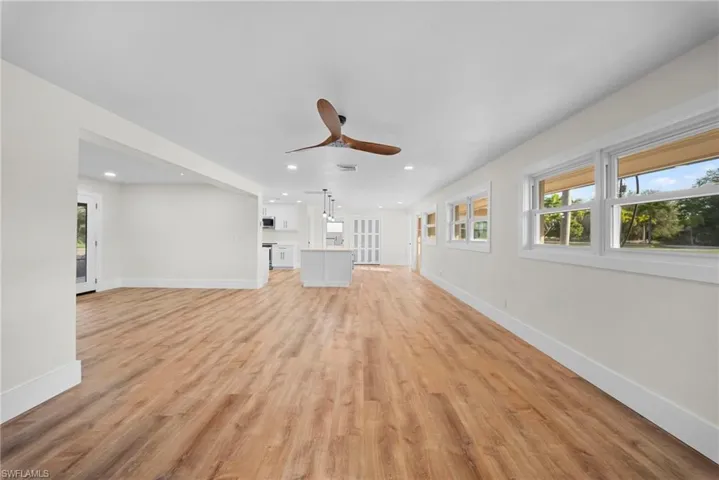 Unfurnished living room with plenty of natural light, a ceiling fan, light wood-style flooring, and recessed lighting