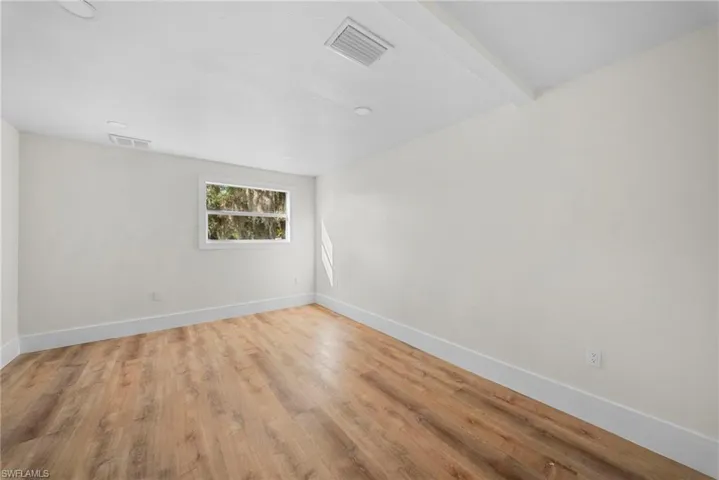 Spare room featuring light wood-type flooring and beam ceiling