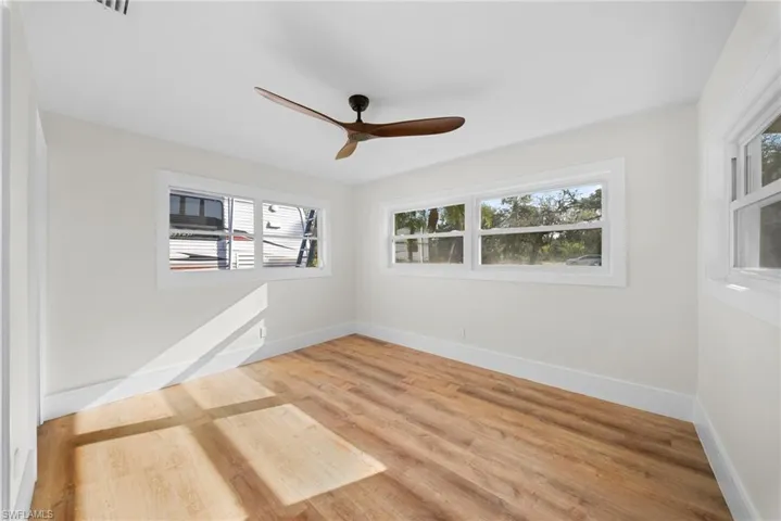 Unfurnished room with light wood-style floors, healthy amount of natural light, and ceiling fan