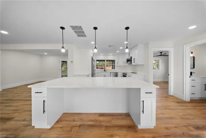 Kitchen featuring white cabinets, light stone counters, and light wood-style floors