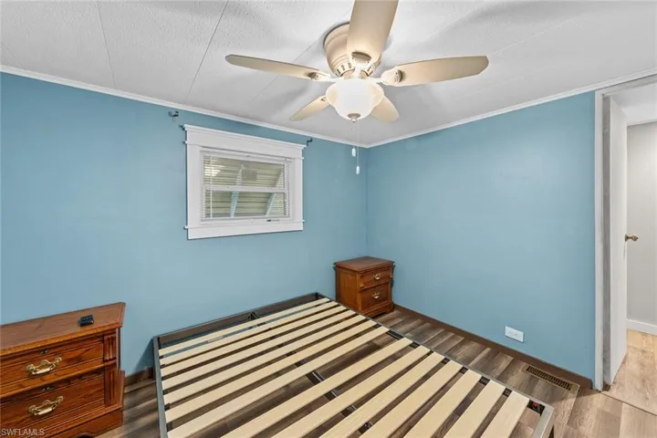 Unfurnished bedroom with ceiling fan, crown molding, and dark hardwood / wood-style floors