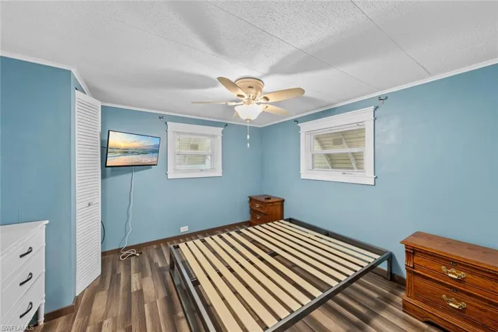 Unfurnished bedroom with dark hardwood / wood-style flooring, ceiling fan, and crown molding