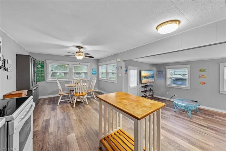 Kitchen with hardwood / wood-style floors, white range with electric stovetop, ceiling fan, and a textured ceiling