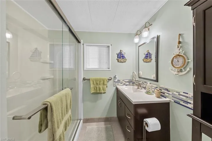 Bathroom featuring vanity, backsplash, tile patterned floors, a textured ceiling, and an enclosed shower