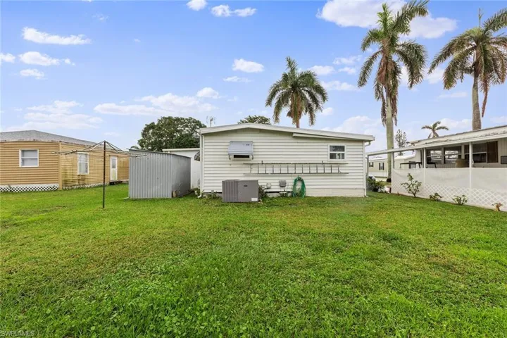 Rear view of house with a lawn, a storage shed, and central AC