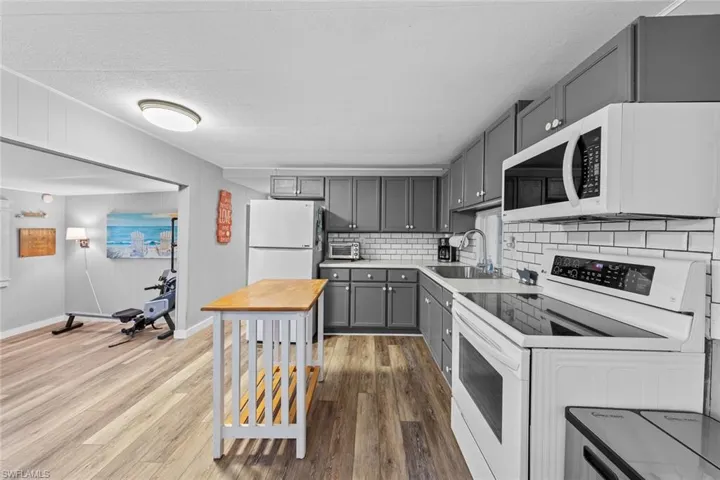 Kitchen featuring backsplash, white appliances, sink, hardwood / wood-style floors, and gray cabinets
