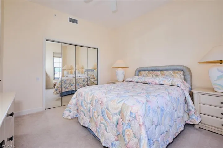 Carpeted bedroom with ceiling fan and a closet