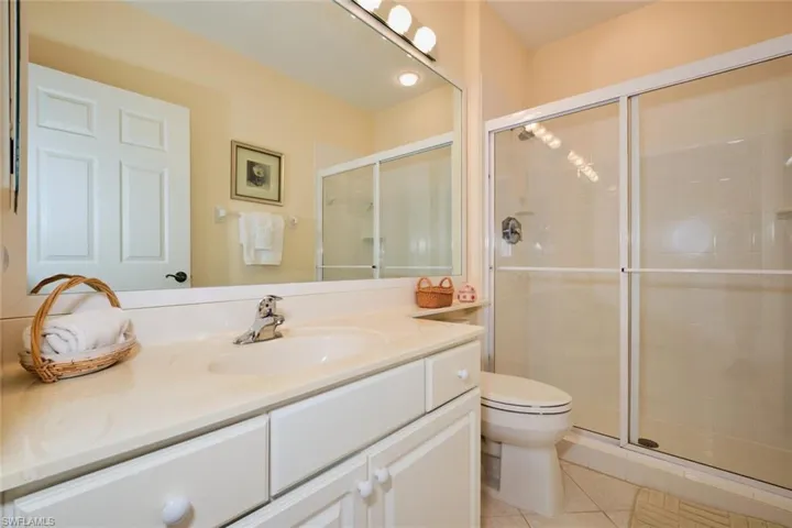 Bathroom featuring vanity, tile patterned flooring, toilet, and an enclosed shower