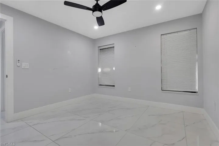 Room featuring large format porcelain tile flooring, two windows with horizontal blinds, recessed lighting, and a ceiling fan