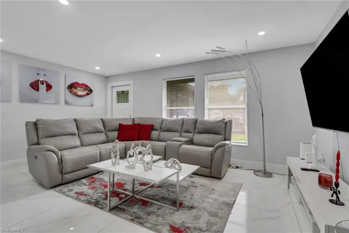 Living area with light gray walls, recessed lighting, white baseboards, and a white door with a clear glass insert