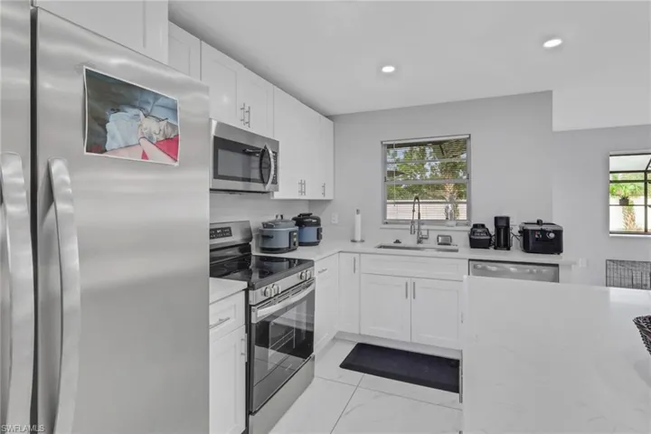 Modern kitchen featuring white cabinetry, stainless steel appliances, light-toned countertops, and recessed lighting