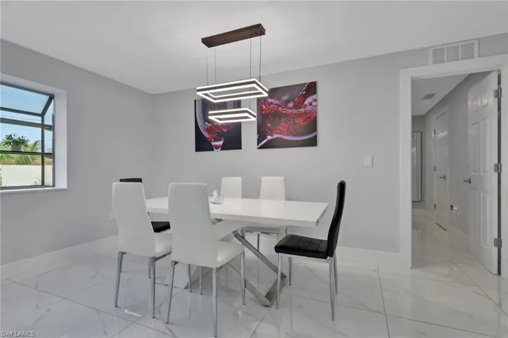 Modern dining space featuring a contemporary chandelier, light gray walls, and large format tile flooring