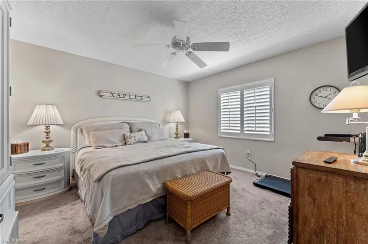 Bedroom featuring baseboards, carpet floors, a textured ceiling, and ceiling fan