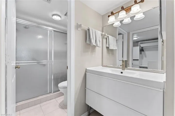 Full bath with tile patterned floors, toilet, a stall shower, and vanity