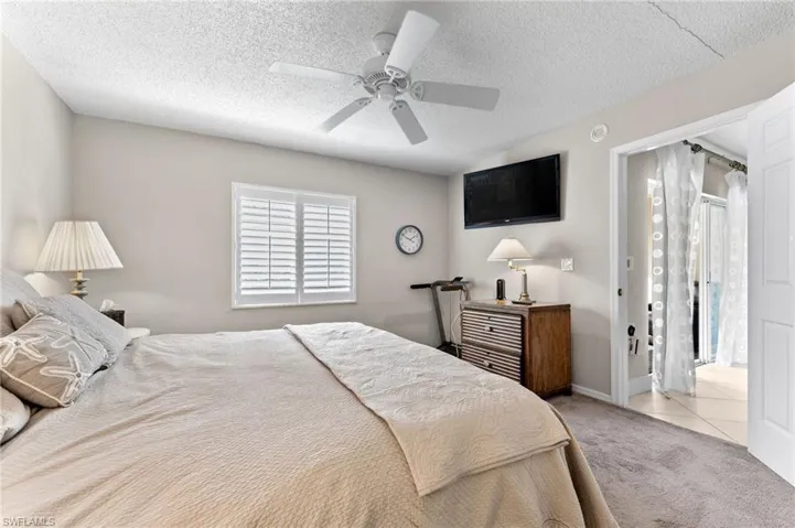 Carpeted bedroom featuring baseboards, a textured ceiling, tile patterned flooring, and ceiling fan