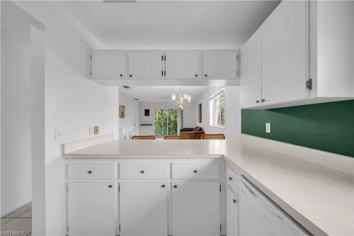 Kitchen with white cabinetry, light countertops, dishwasher, and a chandelier