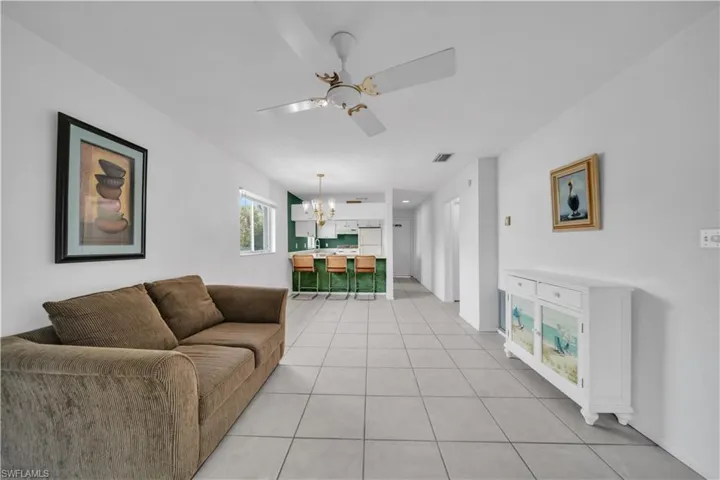 Living area featuring light tile patterned floors, a chandelier, and ceiling fan