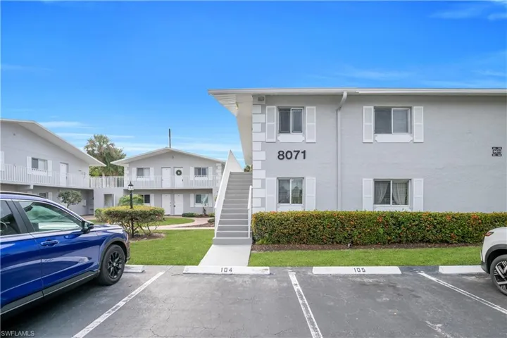 View of property with uncovered parking and stairway