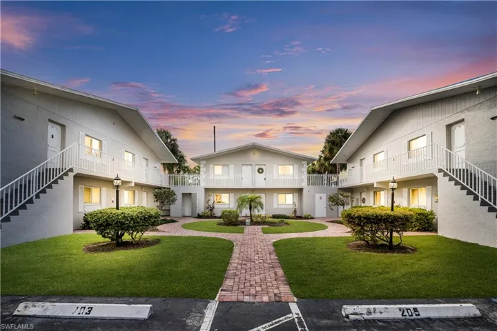 Surrounding community featuring stairs, a balcony, a lawn, and uncovered parking