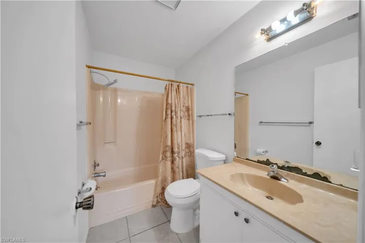 Full bath featuring shower / tub combo with curtain, vanity, and light tile patterned floors