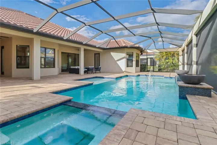 View of screened in  swimming pool with a pool with connected hot tub.