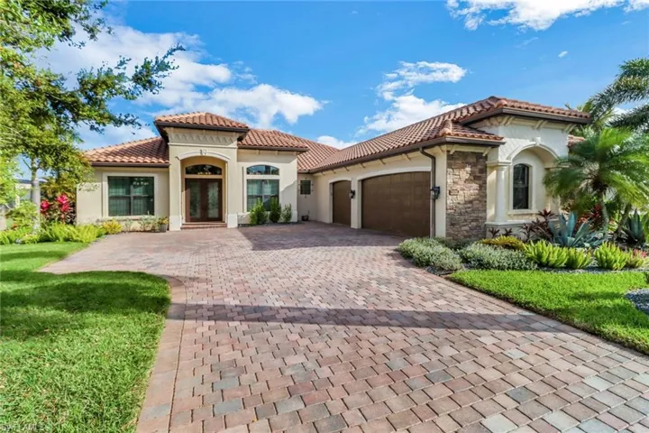 Mediterranean / spanish home featuring a tiled roof, an attached garage, decorative driveway, french doors, and stucco siding