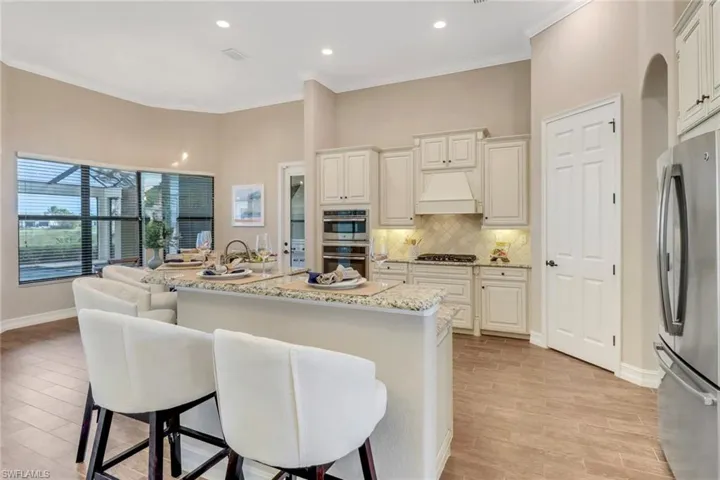 Kitchen with a center island, custom exhaust hood, stainless steel appliances, tasteful backsplash, and a kitchen breakfast bar
