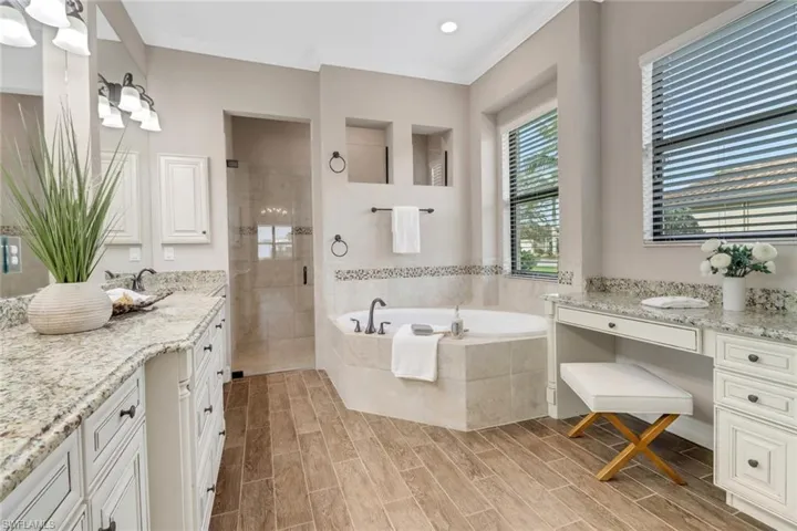 Bathroom featuring a stall shower, wood tiled floor, a garden tub, and two vanities