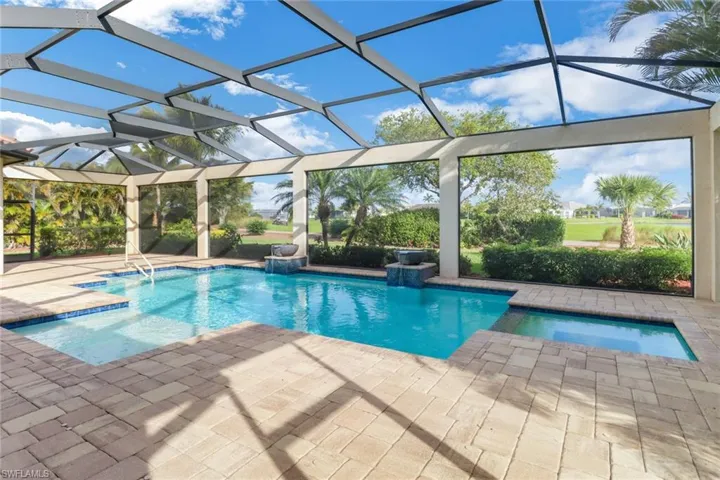 Outdoor pool featuring glass enclosure and a patio