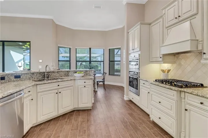Kitchen featuring appliances with stainless steel finishes, a sink, wall chimney range hood, and light wood-style flooring