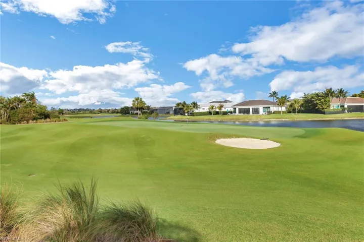 Surrounding community with a water view, golf course view, and a lawn