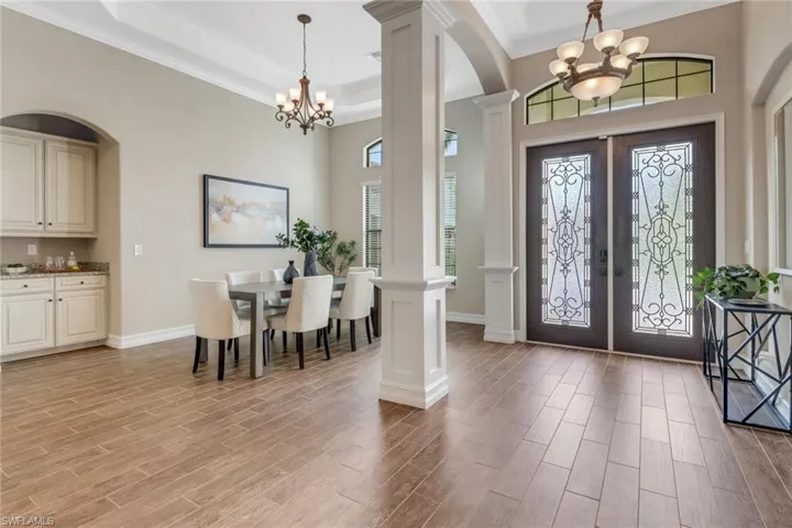 Foyer featuring a notable wood finish floors, ornamental molding, french doors, and decorative columns
