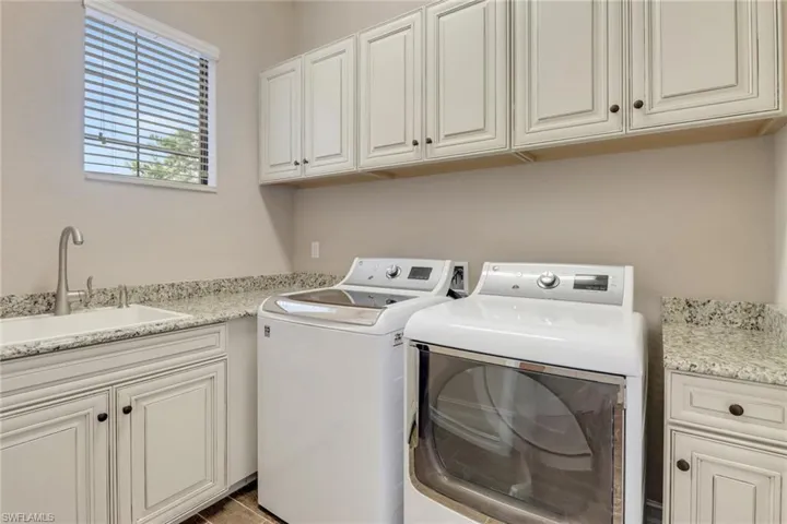 Clothes washing room featuring cabinet space, a sink, and washing machine and clothes dryer