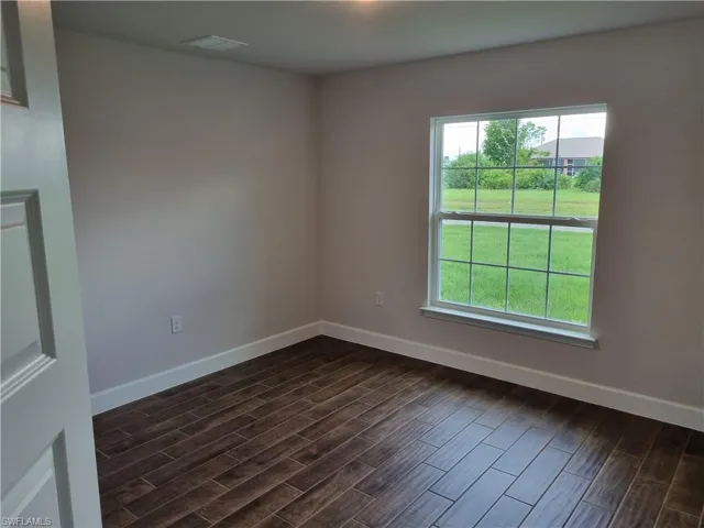 Unfurnished room with plenty of natural light and dark hardwood / wood-style floors