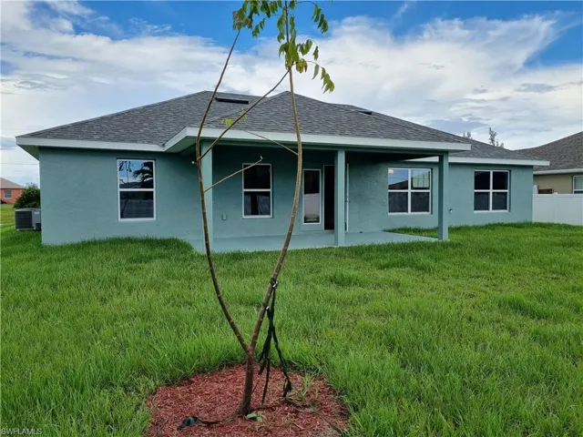 Back of house with a yard, cooling unit, and a patio