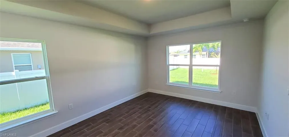 Primary bedroom featuring plenty of natural light and dark wood-type flooring