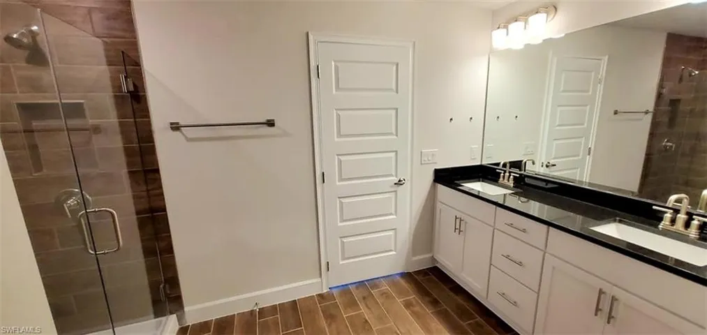 Primary Bathroom with a shower with door, vanity, and hardwood / wood-style floors