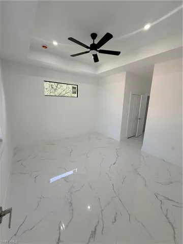 Spare room featuring recessed lighting, light marble finish flooring, a tray ceiling, and ceiling fan