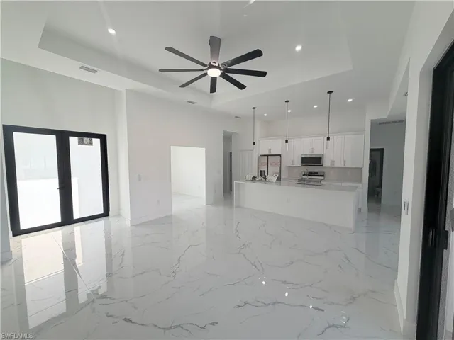 Kitchen featuring a tray ceiling, open floor plan, white cabinetry, and recessed lighting