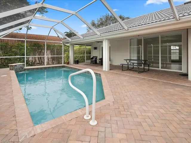 Screened enclosure encompassing a swimming pool with a brick paver deck