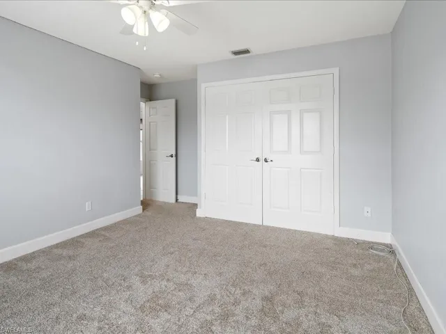 Carpeted interior space featuring light gray walls and white baseboards