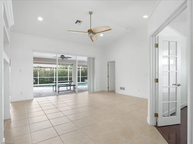 Spacious living area featuring large format tile flooring and vaulted ceilings with a ceiling fan