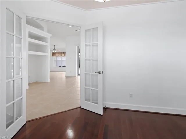 Room featuring rich wood-finish flooring, white walls, and elegant French doors
