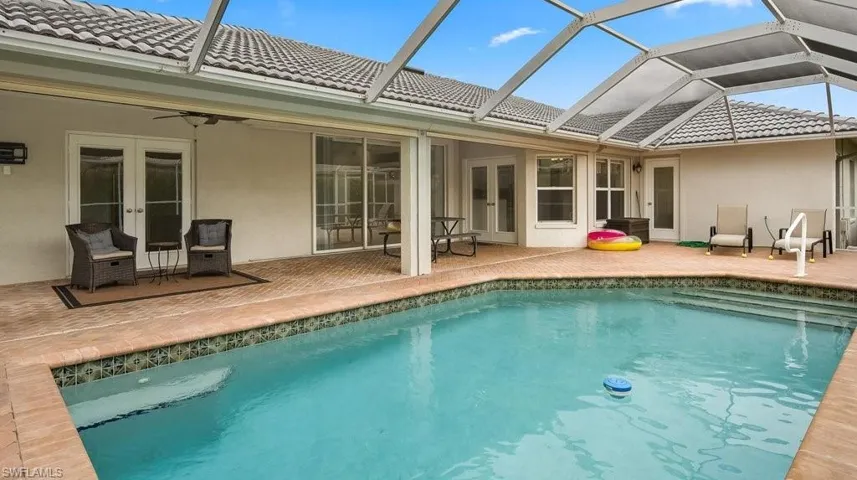 Screened-in swimming pool with integrated steps, surrounded by a brick-paver patio