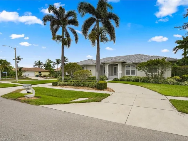 Exterior residence featuring a concrete tile roof, light-toned stucco facade, and a curved concrete driveway