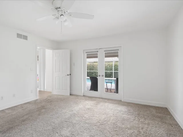 Interior room featuring neutral wall paint, light gray carpeting, and a white ceiling fan