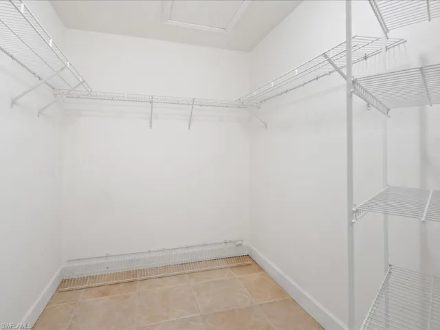 Walk-in closet featuring white wire shelving, hanging rods, and a light-toned tile floor