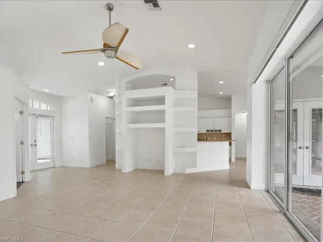 Spacious interior featuring tile flooring, a ceiling fan with integrated lighting, built-in shelving, recessed lighting, and expansive sliding glass doors