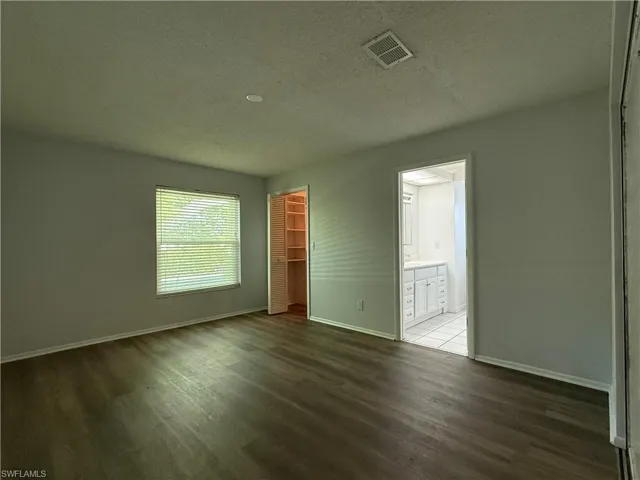 Spacious room featuring wood-finish flooring, neutral wall tones, and recessed lighting